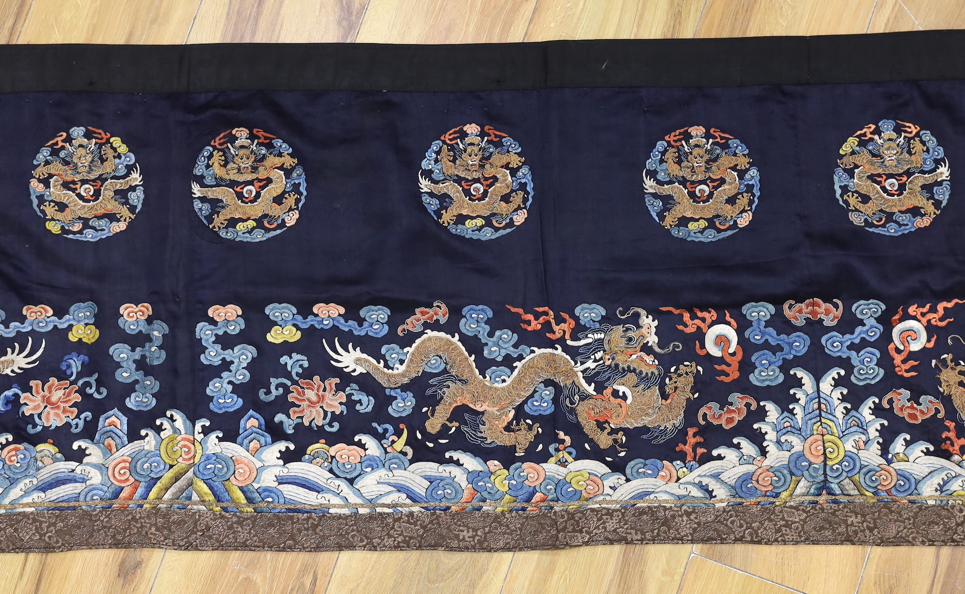 A Chinese long dark blue ground ‘dragon’ altar cloth, late Qing dynasty, polychrome embroidered, celestial dragons and mons amongst stylised clouds, 300 x 50cm